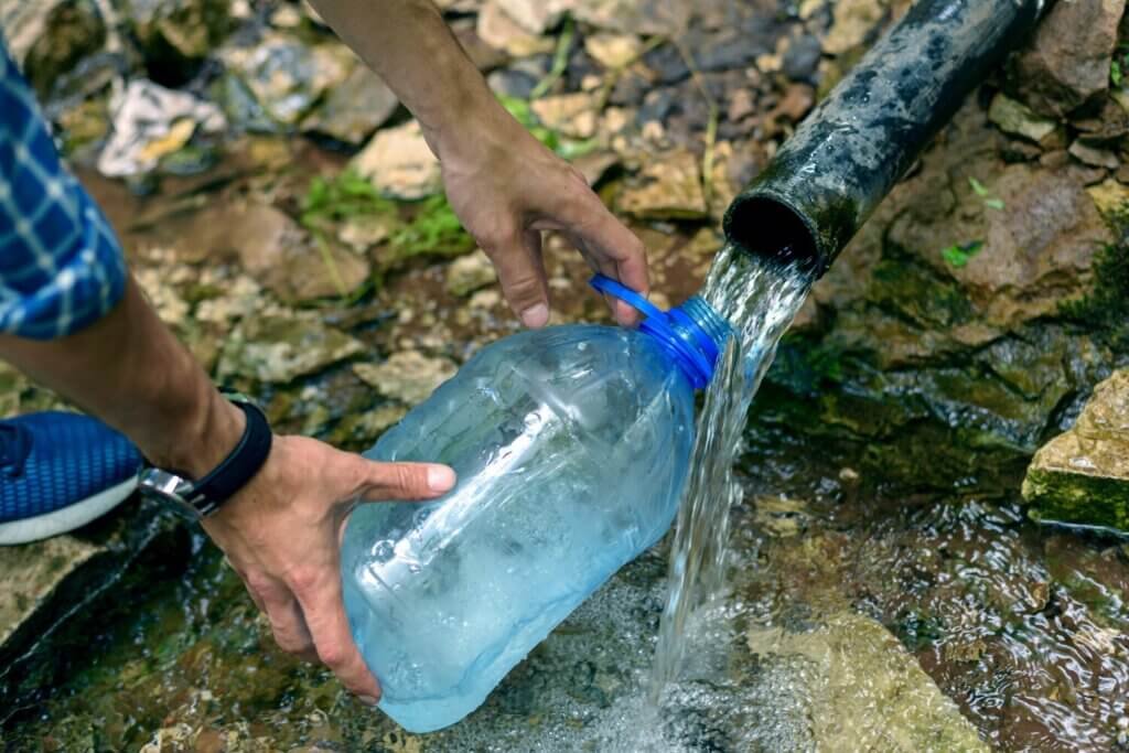 man fills plastic bottle with water from underground source clean water 108611 761 racionamento de agua 3