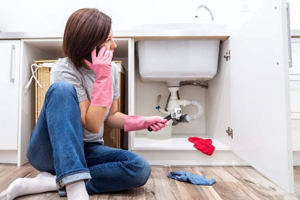 woman sitting near leaking sink sking help by phone 130111 7906